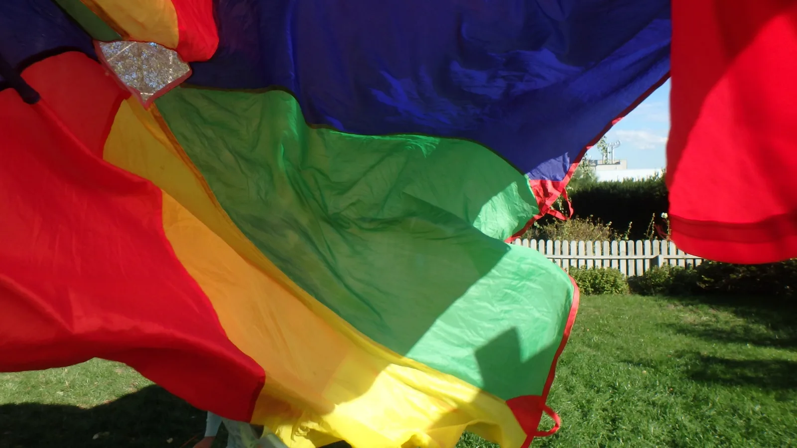 Dzieci bawiące się chustą animacyjną w ogrodzie