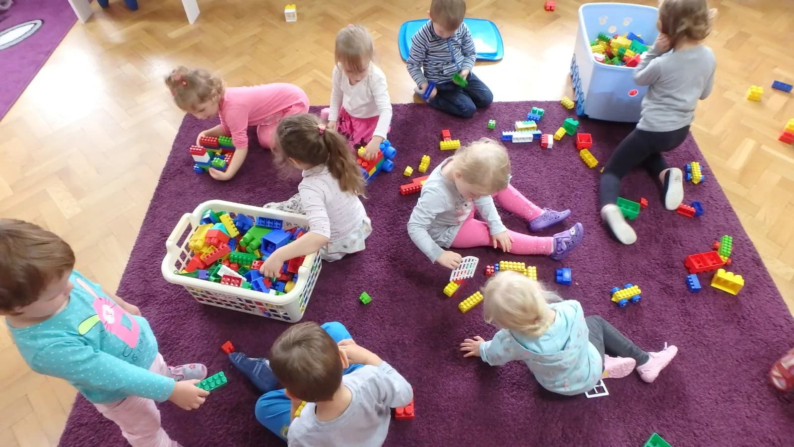 Dzieci bawiące się klockami na dywanie w sali